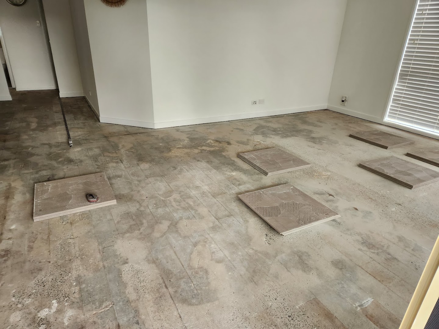 An empty room with tiles set out across the bare floor ready to lay
