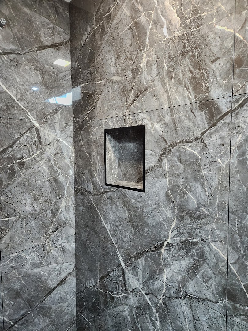 A dark marble-look tiled wall with a recessed shelf set into the tile joint