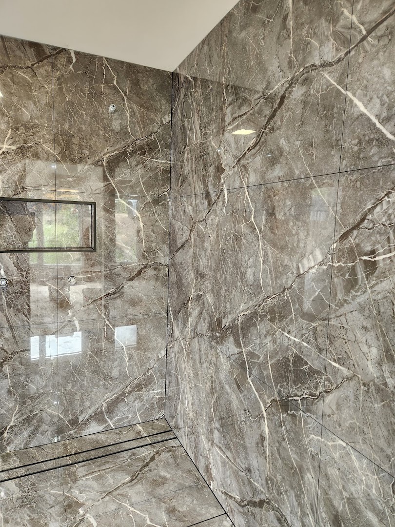 Shower walls tiled in grey marble-look porcelain with a recessed shelf and linear drain