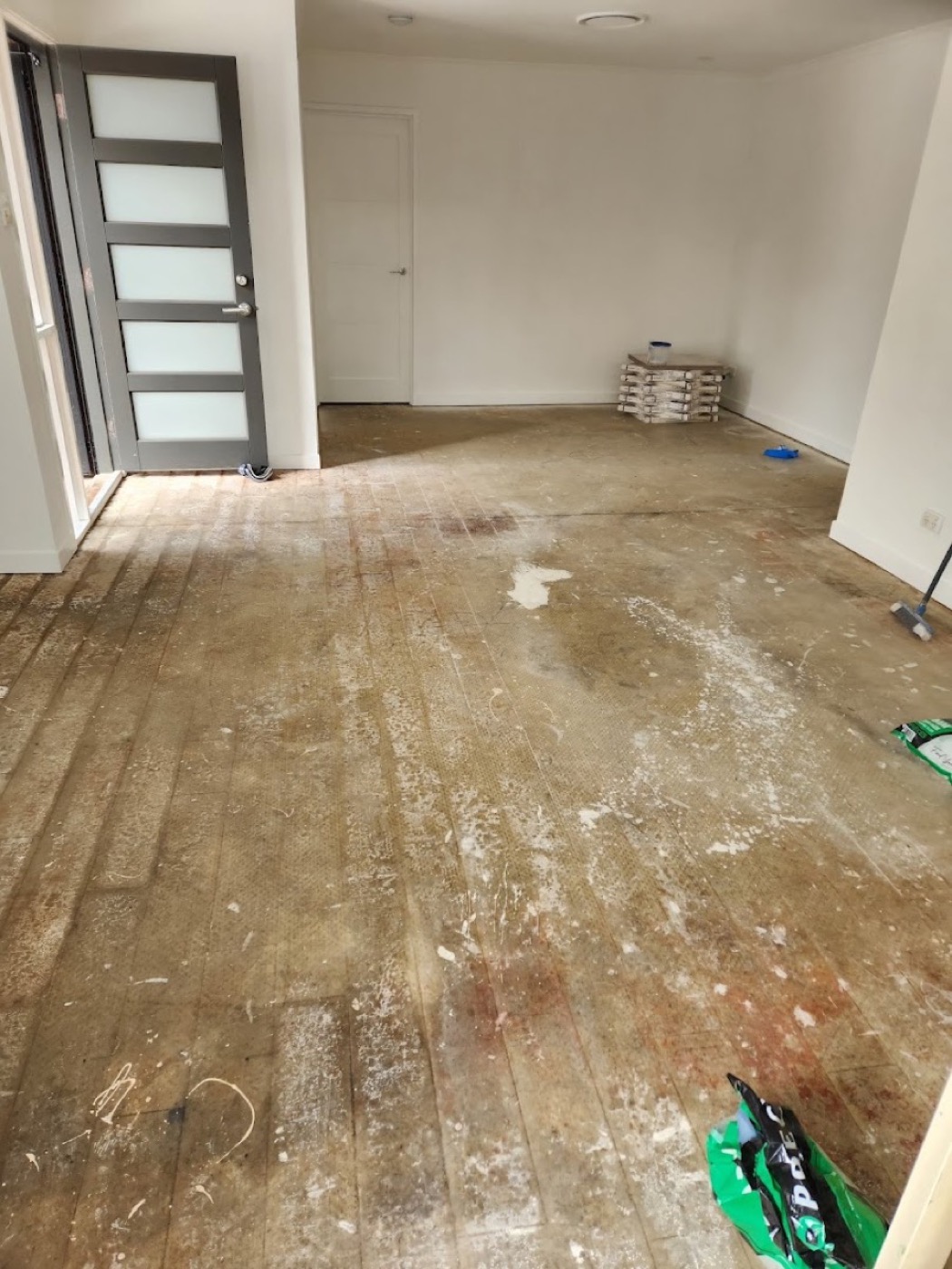 A stripped subfloor being prepared, with old adhesive ground back before tiling