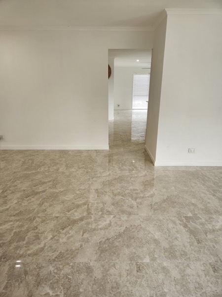 Large-format marble-look floor tiles laid through an empty room and doorway