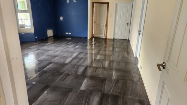 Dark grey marble-look floor tiles in a room with a deep blue painted wall