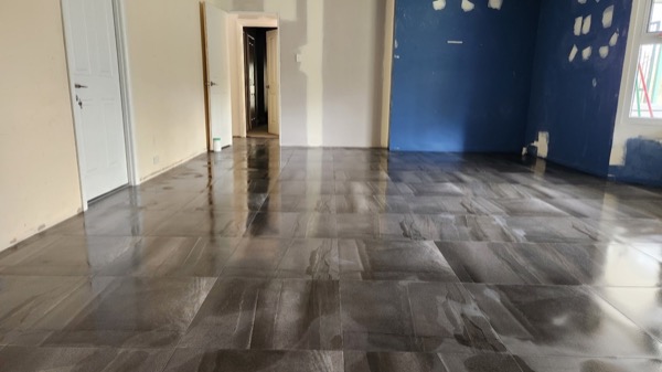 A dark grey marble-look tiled floor running out of a room into a hallway