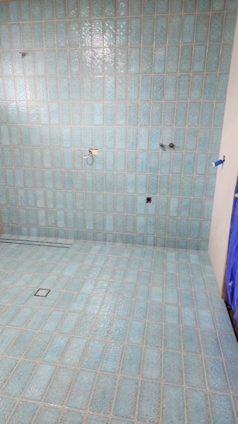 A wall tiled in aqua glazed brick tiles with a fine grout line