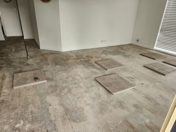 An empty room with tiles set out across the bare floor ready to lay