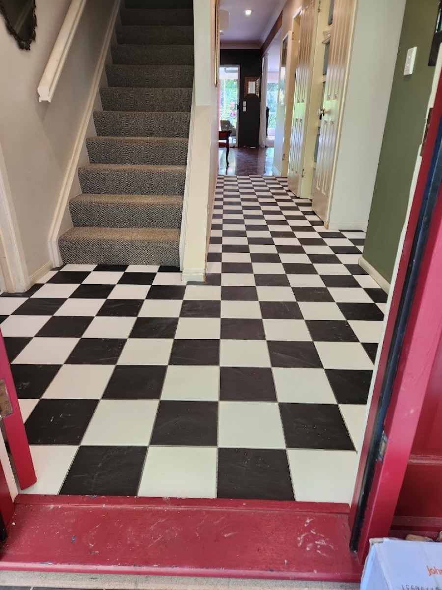 A black and white checkerboard tiled floor at the foot of a staircase