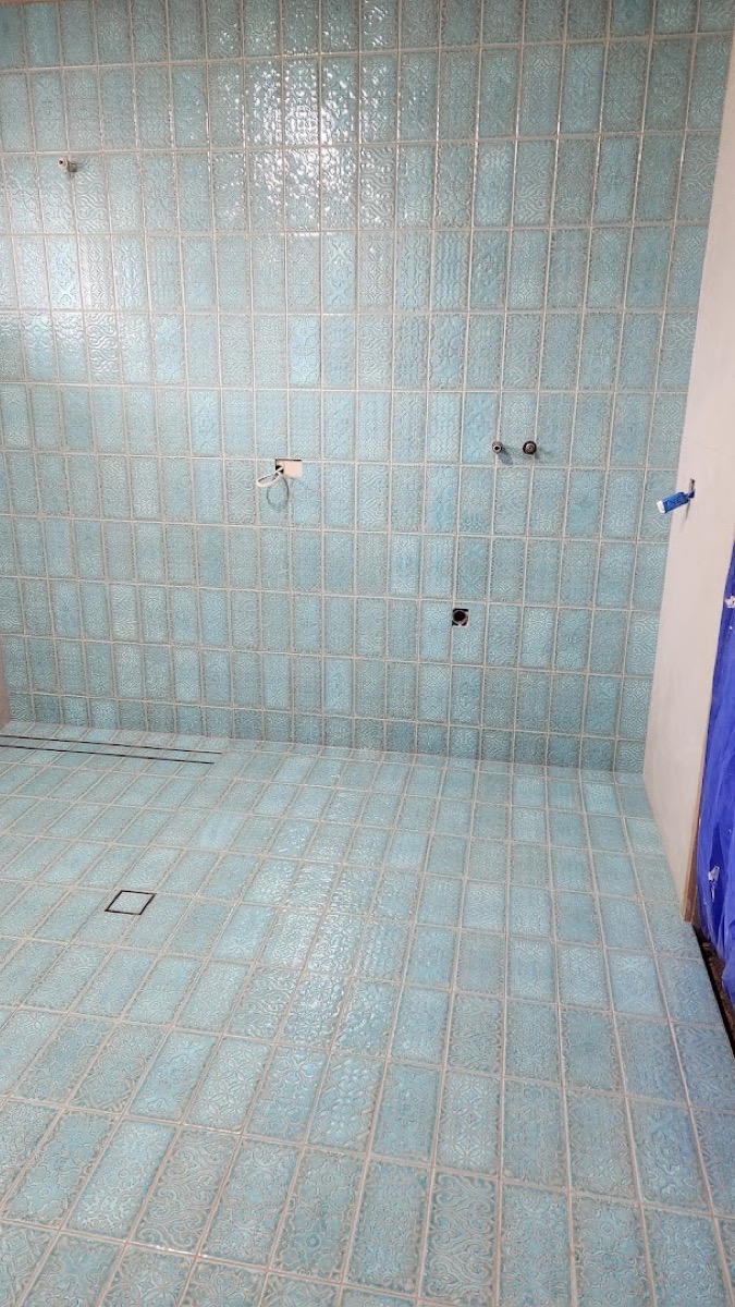 A wall tiled in aqua glazed brick tiles with a fine grout line